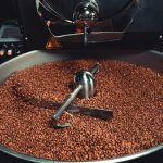 A detailed view of freshly roasted coffee beans inside an industrial roaster, showcasing machinery and process.
